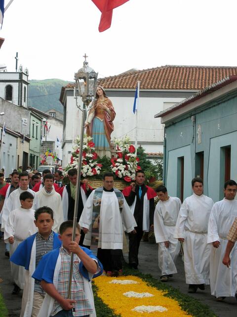 Der Priester umrundet mit Heiligenfigur Bank und Klosterkirche