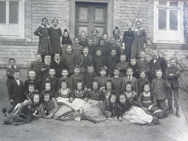 Lehrer KORNMANN (geb. 29.09.1863) mit seiner Klasse um 1920 bis 1925. Mit noch überwiegend Trachten-Trägerinnen; bitte mit Schulklassen-Fotos vorher vergleichen.