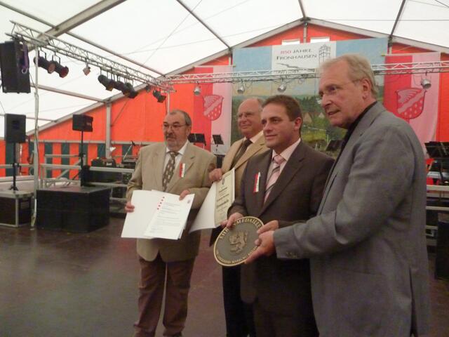 Wieland Schneider (von links), Helmut Jung, Reinhold Weber udn Robert Fischbach zeigen die Auszeichnungen für den Ort Fronhausen.