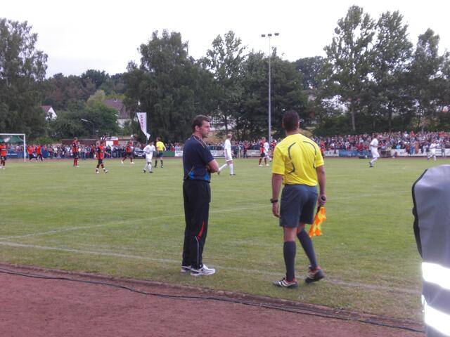 Trainer Skibbe diskutiert mit dem Linienrichter über eine Schiedsrichterentscheidung