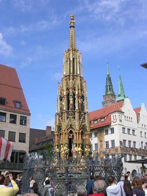 Schöner Brunnen. Von 1389 bis 1396 vom Parlier und Steinmetz Heinrich Beheim erbaut. Die 19 Meter hohe Steinpyramide wächst wie eine gotische Kirchturmspitze aus einem achtseitigen Becken und verjüngt sich über drei Stufen bis zur Kreuzblume.