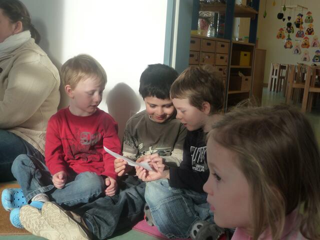 Die Kinder betrachten die Bilder der Ostergeschichte
