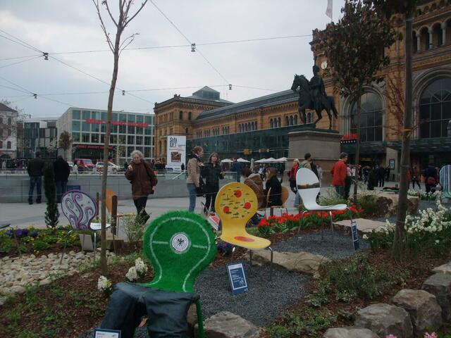 Sitzkunst vor dem Hauptbahnhof in Frühlingsbeete eingebettet