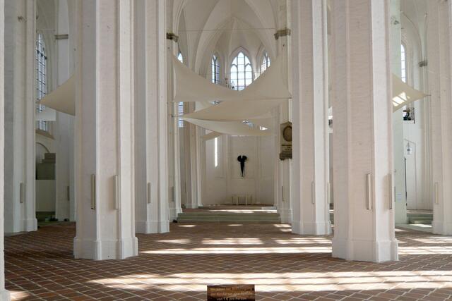 Ein kleines Kruzifix signalisiert die Bedeutung des weißen Raumes als Kirche.
