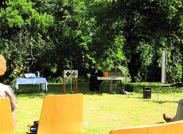 Pastor und Organistin beim Singen im Schatten