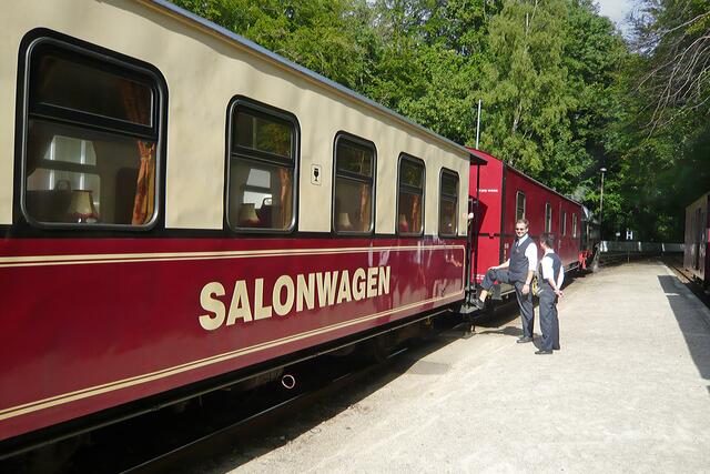 Nostalgische Einrichtung des Salonwagens mit Holzverkleidungen, roten Samtpolstersitzen, Gardinen...