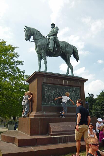 Die Jüngsten nutzen im Schlosspark das Reiterstandbild (Kaiser Wilhelm I.) von 1896 auf ihre eigene Art.