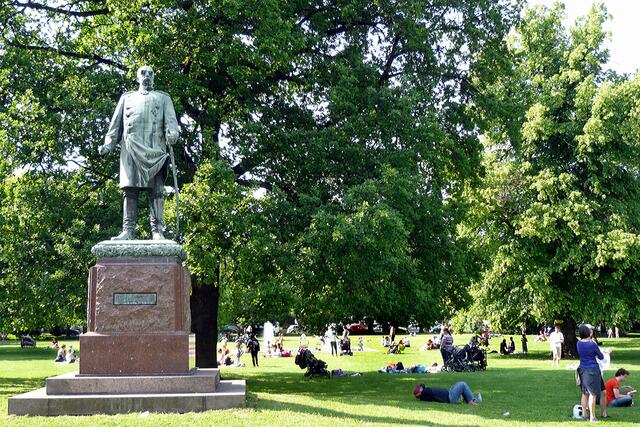Unter den alten Bäumen des kleinen Parks in der Nähe des Opernhauses erfreuen sich viele Familien mit kleinen Kindern an diesem Sommertag. Das Bismarck-Denkmal stammt aus dem Jahr 1897.