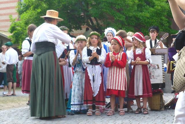 Kinder mit ihrer Lehrerin singen fröhliche Kinderlieder