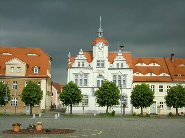 Ostritz: Weißes Rathaus vor schwarzem Himmel.