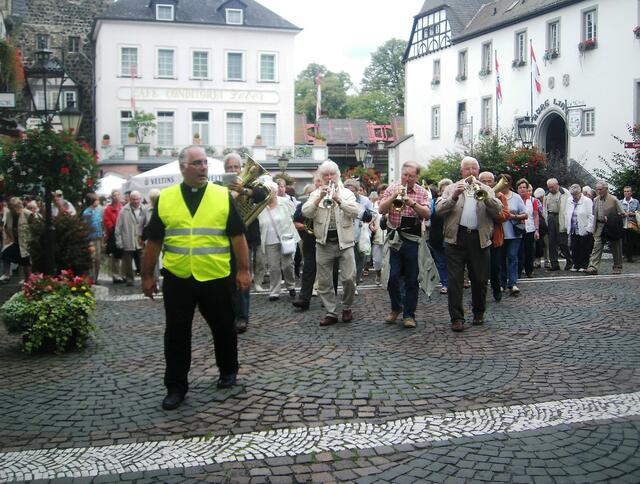 Vorweg der Pastor in grüner Warnweste, ihm folgen ein Fanfarenchor und danach Marienlieder singend die riesige Pilgerschar.