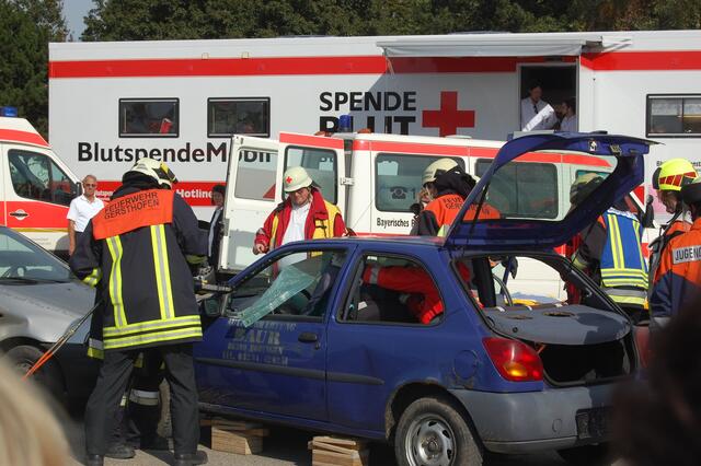 Der Notarzt versorgt im Auto die verletzte Person, die Feuerwehr arbeitet mit der Rettungsschere