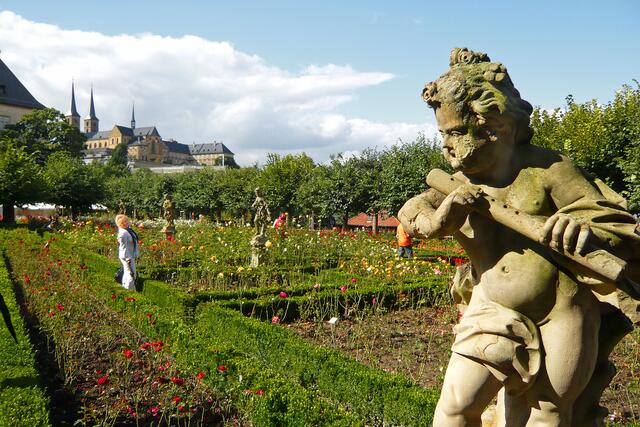 Die prächtige Gartenanlage (im Hintergrund St. Michael, das ehemalige Benediktinerkloster) lädt zu Erinnerungsfotos ein (rechts die Skulptur Knabe mit Flöte).