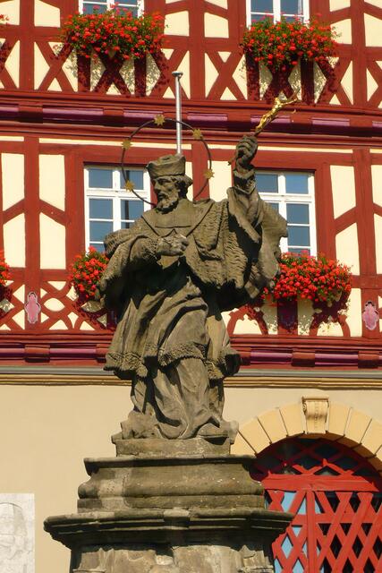 Auf dem geschwungenen Steinsockel des Stadtbrunnens steht ein steinerner St. Nepomuk mit dem „Marktkreuz“, die Statue vermutlich aus einer Zeit um 1730.