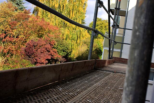 Blick von meinem Balkon durch das Gerüst auf die herbstlich gefärbten Bäume der Nachbarn