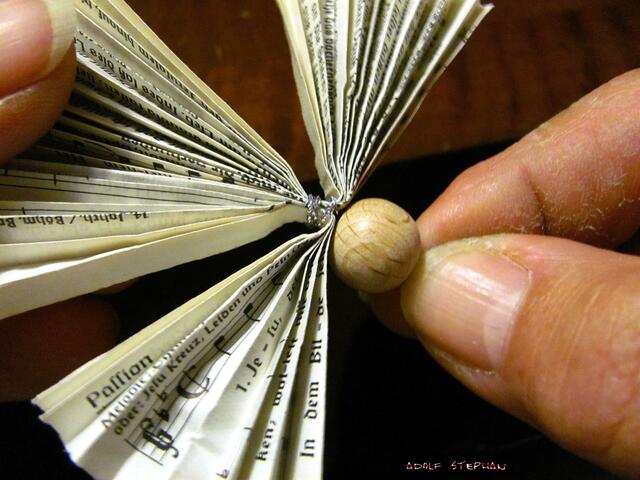 Die Kugel auf den Kleberpunkt pressen und das Band in der gewünschten Länge verknoten