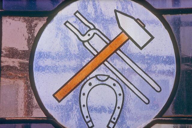 Symbole im Kirchenfenster: Hammer, Schmiedezange und Hufeisen