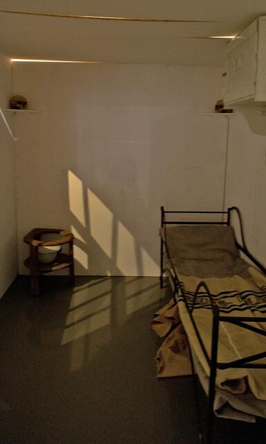 Seine Zelle. Unter dem Bett liegt ein Sack voll Knochen, an den Wänden 4 Schädel seiner Opfer.