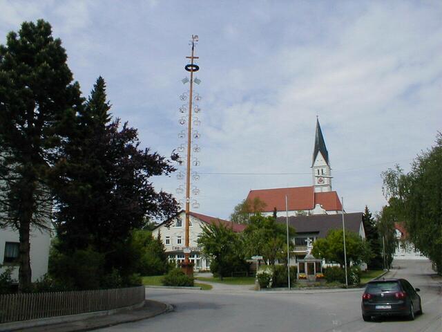 Gemeindeverwaltung mit Maibaum und Kriegerdenkmal sowie im Hintergrund die Pfarrkirche St. Martin
