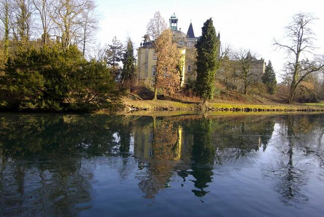 Der frei zugängliche Schlosspark hat eine Größe von über 80 Hektar und umgibt das Schloss von allen Seiten. Wir bummeln entlang des Burggrabens und blicken auf den Westflügel.