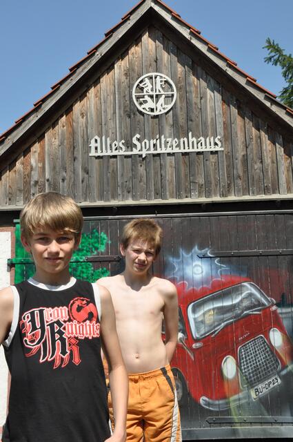 Steven Stumpf und Jason Fiesel vor dem alten Spritzenhaus mit dem BU Feuerwehrfahrzeug an der Fassade.