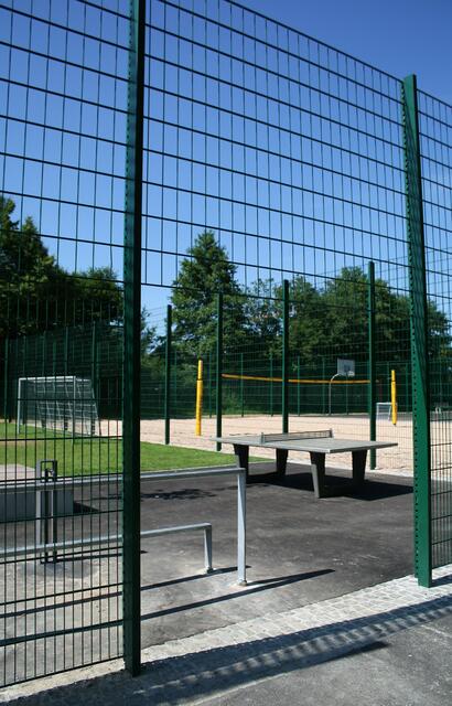 *lach* ... "hinter Gittern"?   Ein 4 Meter hoher "Ballfangzaun" sorgt für Spielfeldtrennung und Sicherheit.