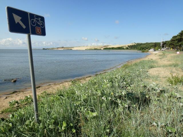 Schild des Europaradwegs E10 vor den Dünen des Ferienortes Nida (Litauen).