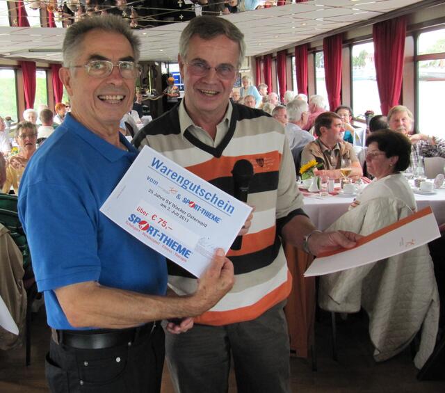 Herr Podella überreicht Spartenleiter Gerd Seifried einen Warengutschein über 75 Euro für die Gesundheitssparte