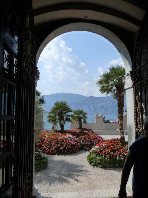 dieser Blick ist umwerfend und zieht einem einfach an, man läuft in der Gasse und schaut durch eine Halle und sieht über Blumen und Palmen den Gardasee und die anschließenden Berge