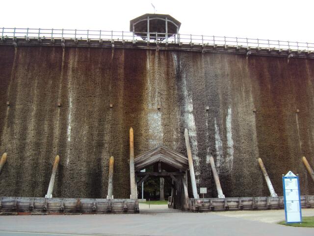 Durch ein Tor kann das alte Werk passiert werden. Im Turm hängt eine Uhrglocke.