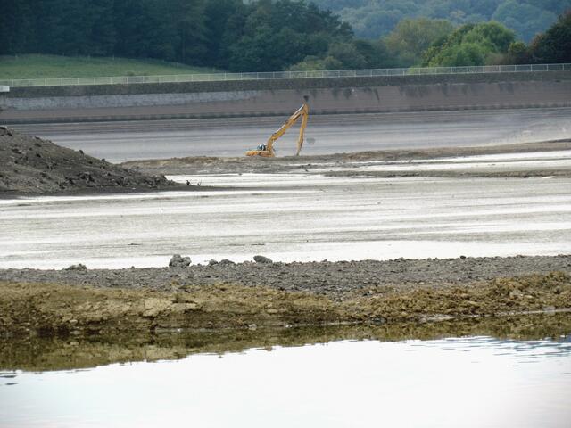 Der leere See vor der Staumauer wird mit einem Bagger bearbeitet