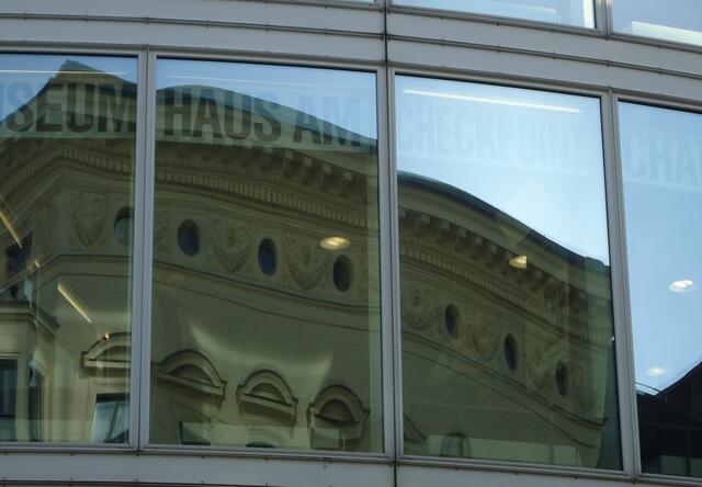 Alte Gebäude spiegeln sich in der Glasfront am Checkpoint Charlie