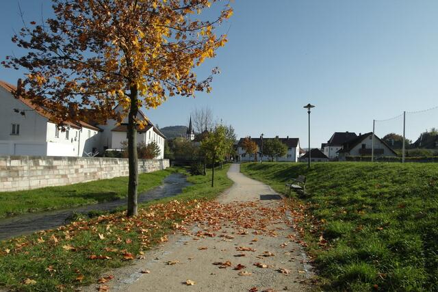 Der Spazierweg führt neben dem Lauterbach entlang, im Hintergrund der Kirchturm der katholischen Kirche.