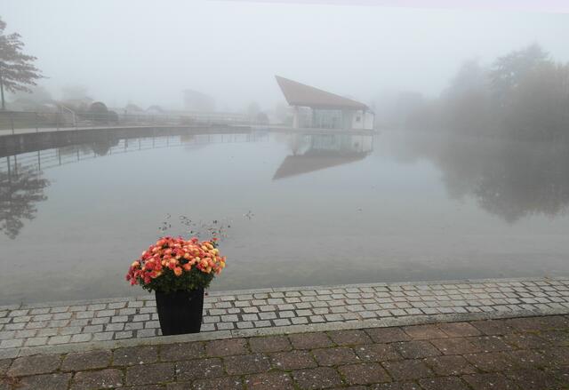 Die Seebühne des Kurparks spiegelt sich trotz des Nebels noch deutlich im Parksee.