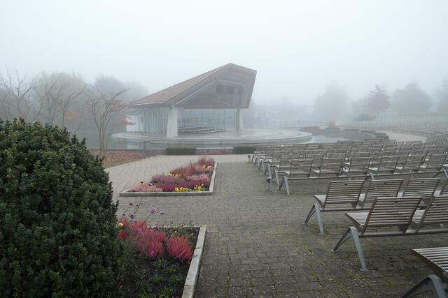 Die meisten der 999 Sitzplätze vor der Bühneninsel inmitten des Parksees werden durch das Nebel-Grau-in-Grau unsichtbar.