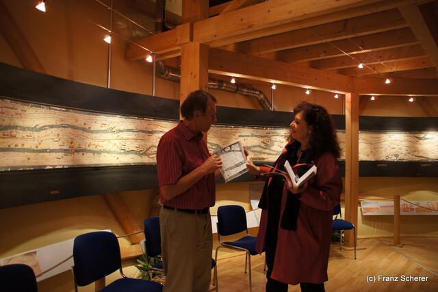 Das Mercateum in Königsbrunn. Kulturwissenschaftler Dr. Dr. Wolfgang Knabe im Gespräch mit myheimat-Reporterin Sabina Scherer vor der Castorius-Karte, bekannt als Peutinger-Karte, ein Facsimile des Originals um 350 n. Chr. mit 120.000 km Handelsstraßen des Römischen Reiches die darüber hinaus bis an den Golf von Bengalen führen.