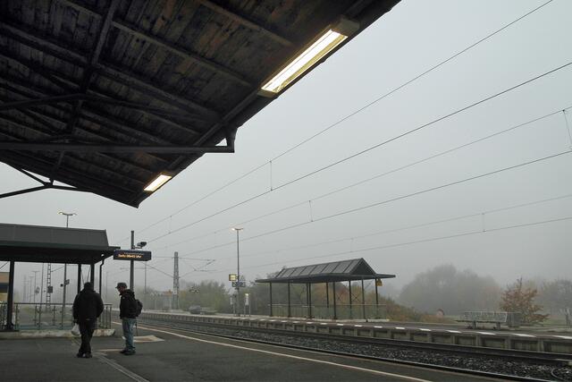 Auf dem Bahnsteig warten ein paar Pendler auf ihre Zugverbindungen in Richtung Bamberg bzw. Lichtenfels.