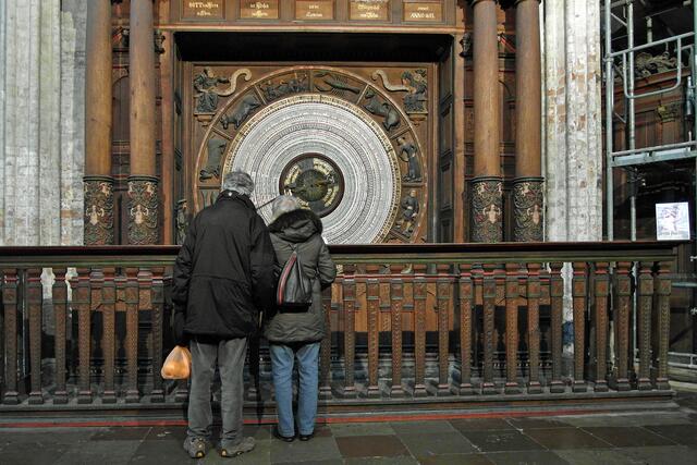 Die untere Hälfte der Uhr wird von der Kalenderscheibe beherrscht, die von den Figuren der vier "Weltweisen" (hier nicht näher bezeichnet) eingerahmt wird. Diese halten Spruchbänder in den Händen, auf denen steht: "Ein Tag saget's den andern und eine Nacht thut's kund den andern: O Mensch, bedenk das Ende, so wirst du nimmer übel thun!"“