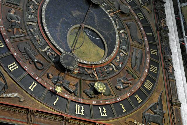 In der Mitte zeigen zwei große runde Metallscheiben, die übereinander liegen, die Mondphasen an: Neumond = schwarzes Gesicht, Vollmond = gelbes Gesicht.