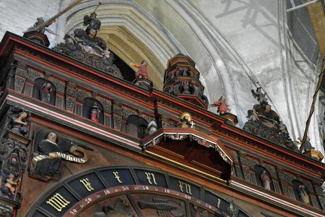 Oben befindet sich in der Mitte der Apostelumgang, der jeden Mittag um 12 Uhr beobachtet werden kann. Sechs Apostel stehen links und rechts der Plattform; sechs treten aus einer Tür heraus, ziehen in einem Bogen um Christus (Bildmitte), wenden sich ihm kurz zu, lassen sich segnen und verschwinden wieder hinter der Tür.