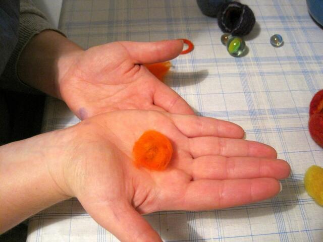Um die Glaskugel wird eine Schicht gezupfter  Wolle (Kammzug) gelegt.