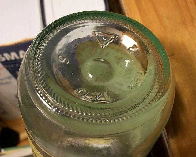 Das Dreieck ist das Erkennungszeichen der Glashütte Gebr. Stoevesandt, Rinteln. Mit dem Abfüller Pott-Rum bestand eine Zusammenarbeit über die Straße hinweg