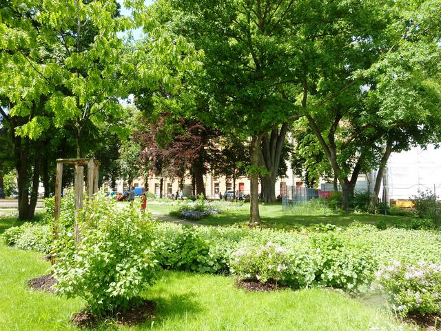 Parklandschaft; im Hintergrund ein zum Wohnhaus umgebautes Fabrikgebäude