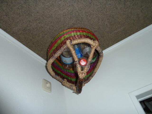 Ein Korb mit Wollkneuel steht oder hängt in der Ecke.