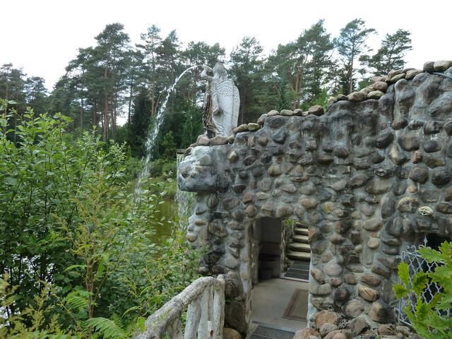 Hier steht ein Engel der Wasser in einen Teich spuckt.