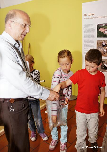 Botschaft an die Zukunft. Kinderprogramm zur Sonderausstellung "Ausgegraben - Archäologie am Friedberger Lechrain" im Museum im Friedberger Wittelbacher Schloss - Museumskustos Hans Beil verteilt Materialproben