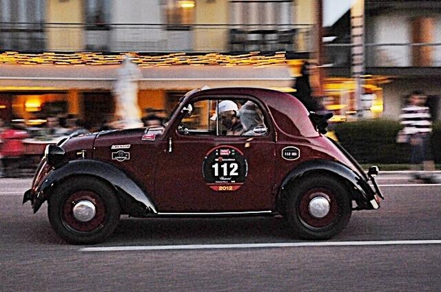Die Lebenshilfepiloten beim traditionellen Strassenrennen Mille Miglia in Italien, in rasanter Fahrt durch Ortschaften in denen Scharen von Zuschauern jubelten.