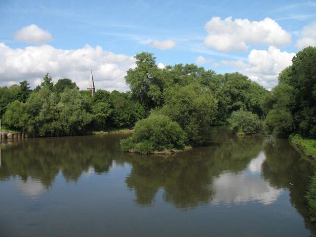 Der Blick vom herrenhäuser Wehr auf die Leine. Über den Bäumen der Turm der Nikolai-Kirche in Limmer.