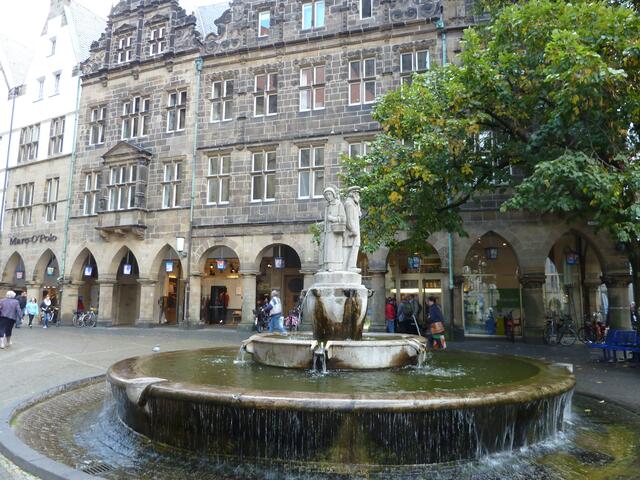Ein Brunnen vor der alten Häuserreihe.