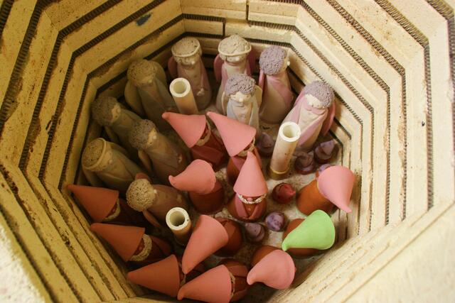 Die unterste Schicht Figuren im Brennofen. Auf die drei Stützen, die man dazwischen sehen kann, wird eine Schamottplatte gelegt, auf die man weitere Figuren setzten kann. so geht es weiter, bis der Ofen voll ist.